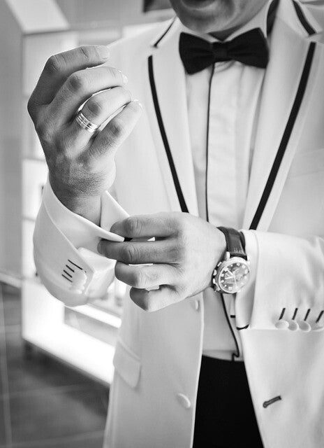 Groom in white dinner jacket adjusting his cufflink